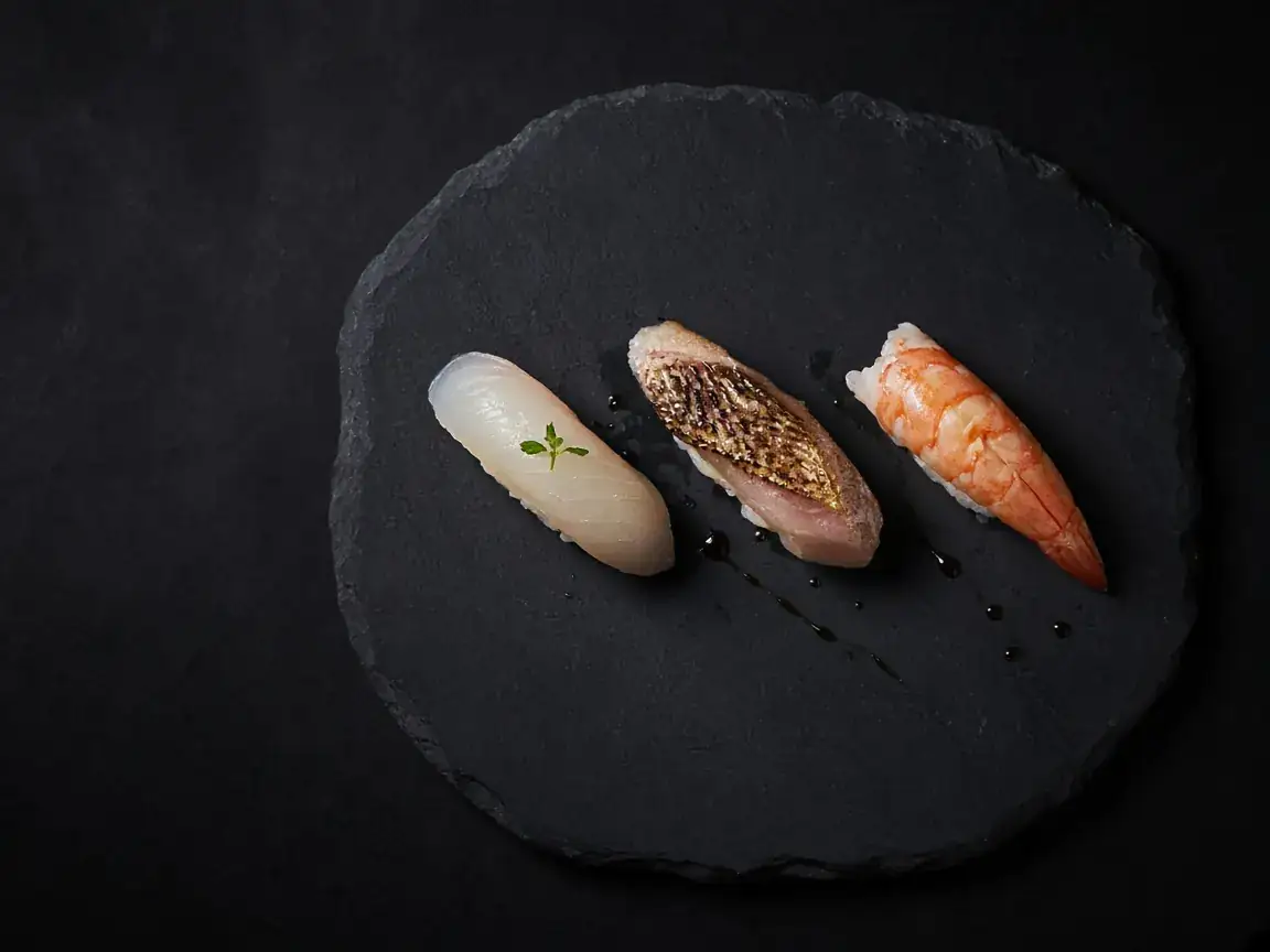 Three nigiri on a dark slate plate